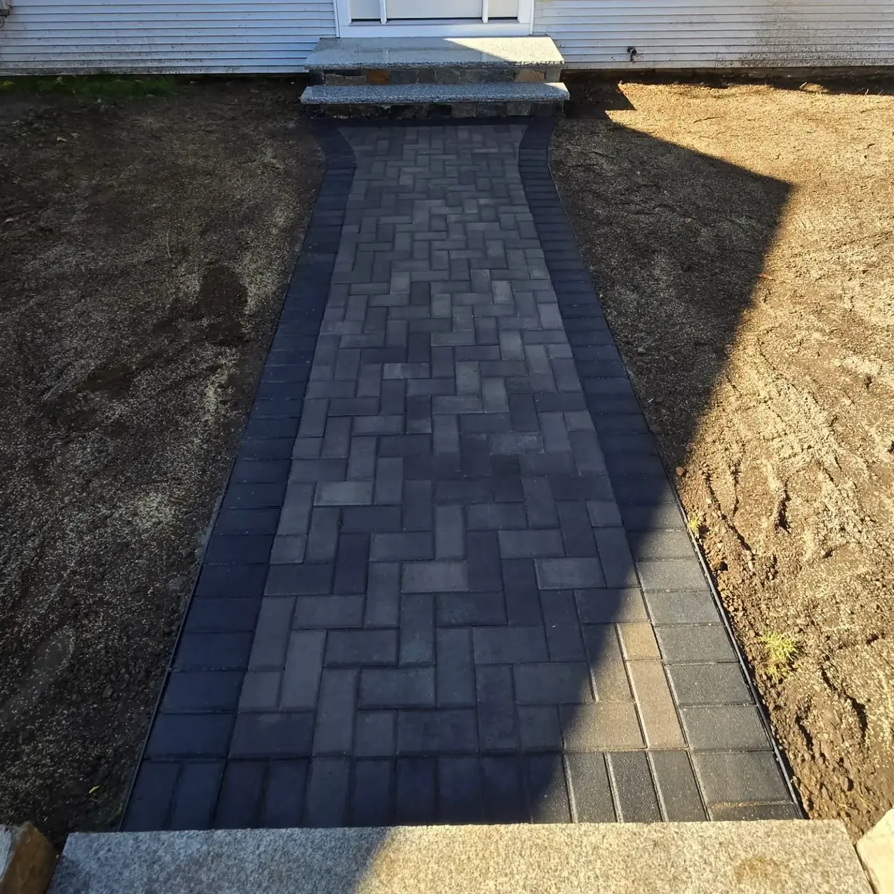 Narrow dark paver walkway leading to front steps