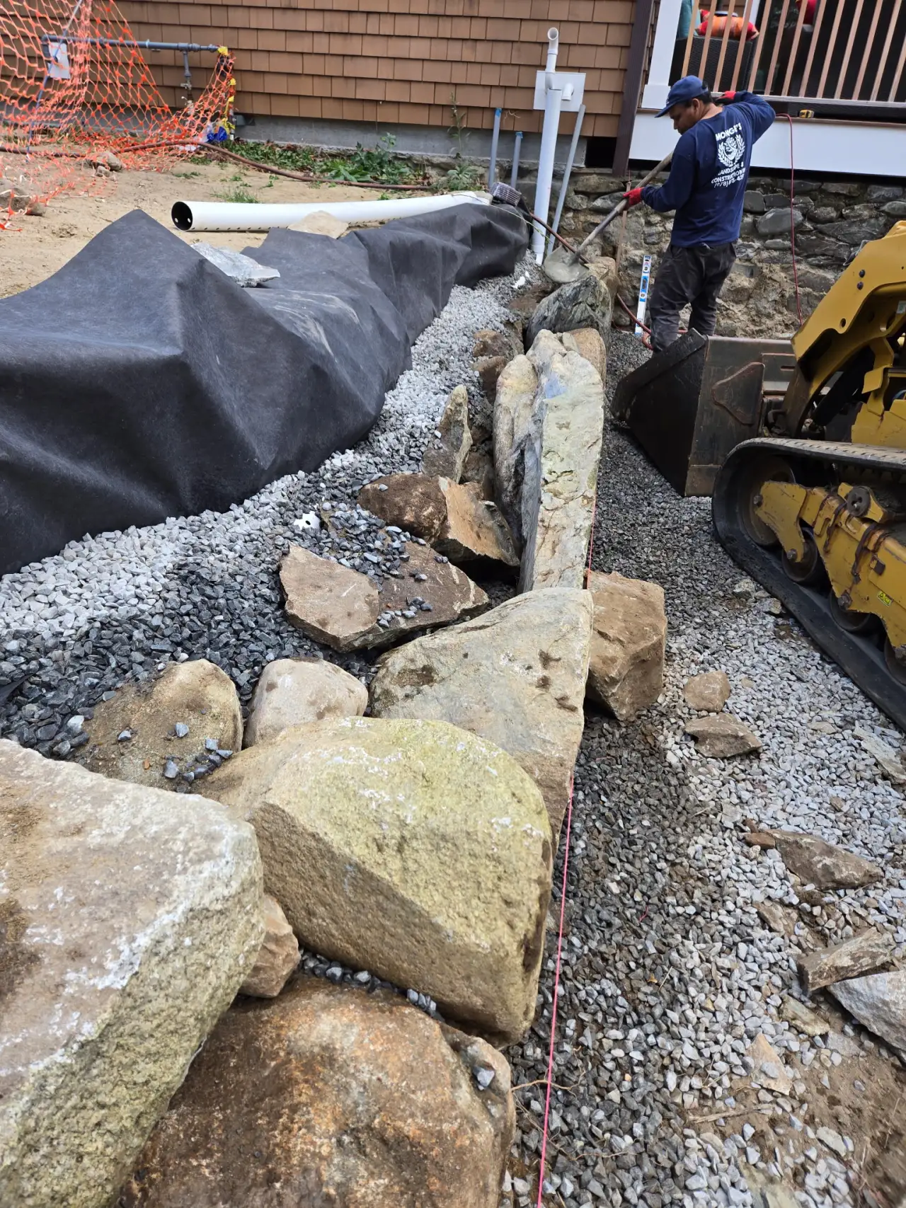 Stone retaining wall construction with level line and drainage — Monges Landscaping