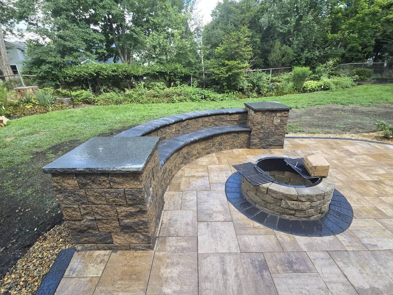 Patio with a circular fire pit and curved seating wall in Needham, MA