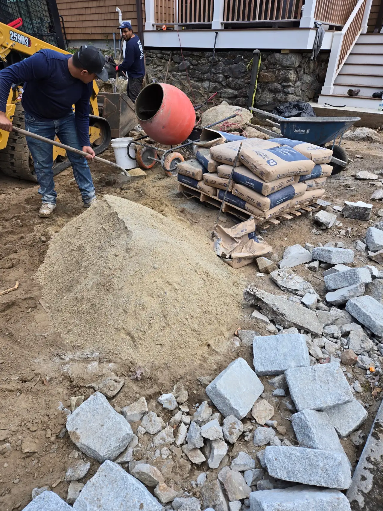 Workers mixing cement for stone wall construction