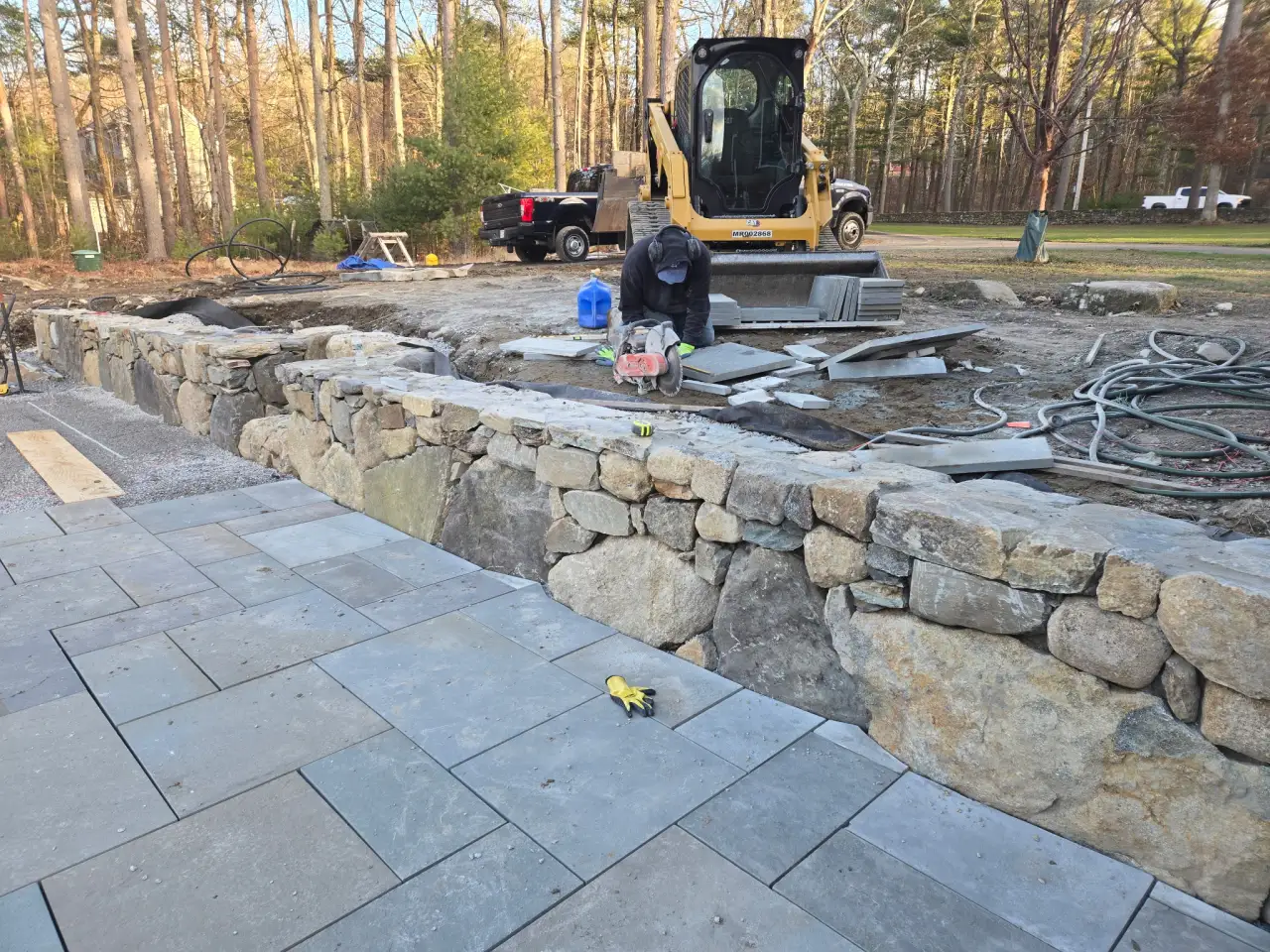 Stone retaining wall with bluestone paver patio installation